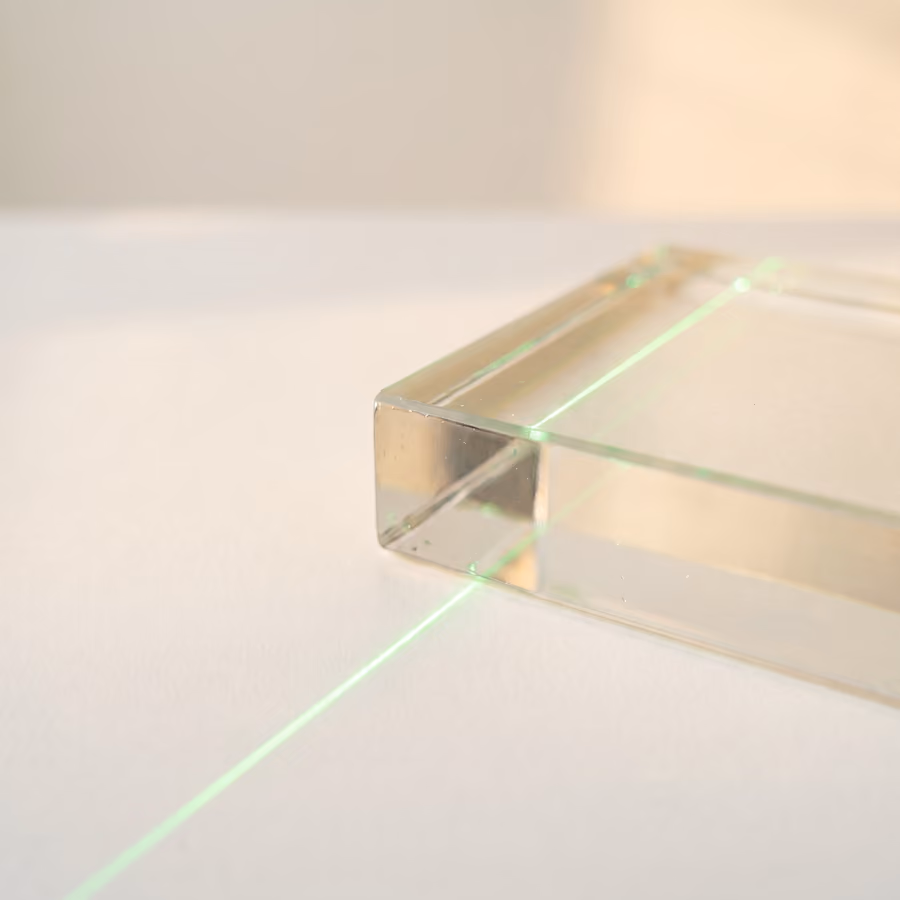 Rendering of an optical glass block refracting a single green line of light in warm daylight